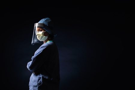 a doctor in mask and full shield looking tired