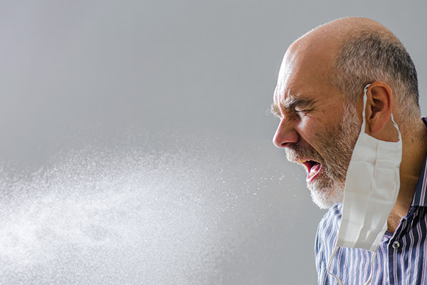 adult person sneezing without covering their mouth, many sneeze particles in air