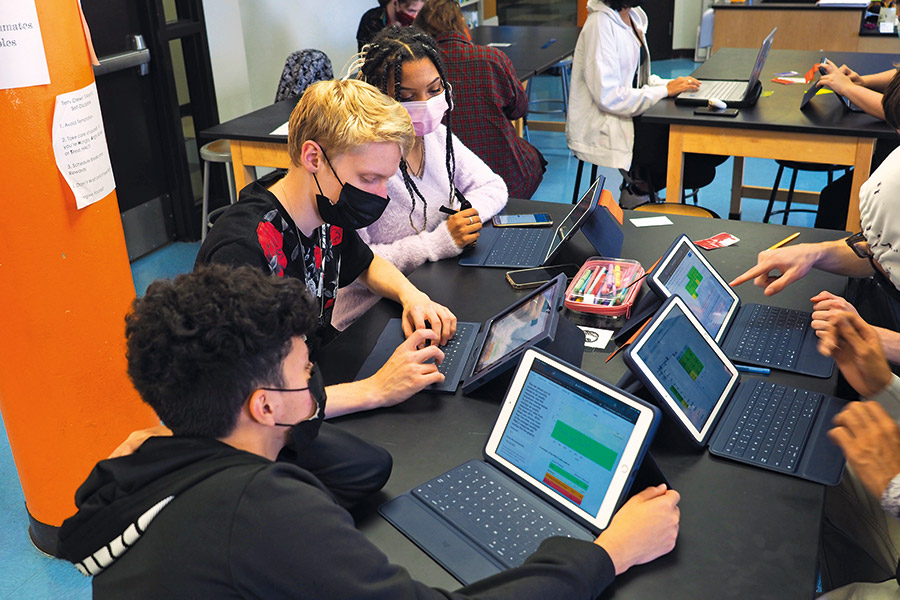 students collaborating at desk with computers